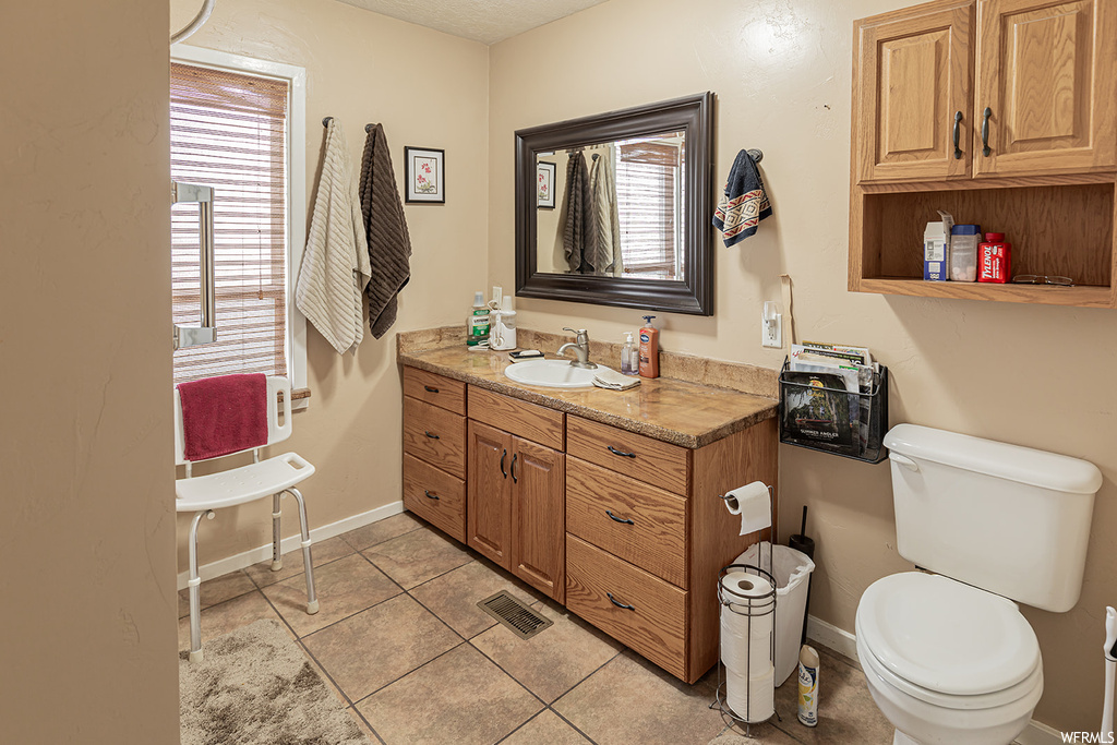 Bathroom with vanity, a healthy amount of sunlight, tile floors, and toilet