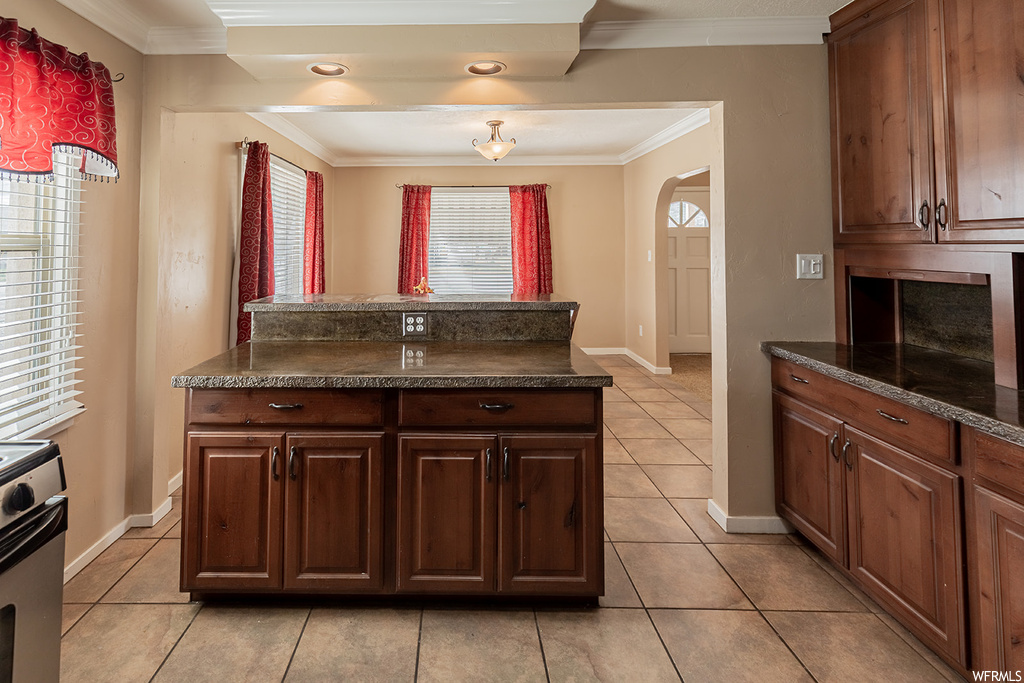 Kitchen with light tile floors, range with electric stovetop, and ornamental molding