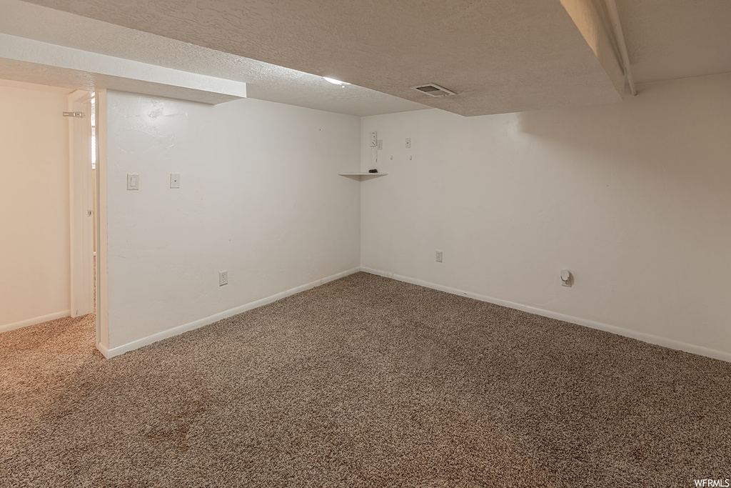 Basement featuring a textured ceiling and carpet