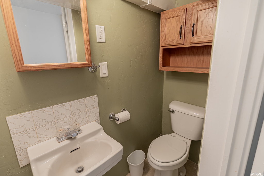 Bathroom featuring backsplash, toilet, and sink