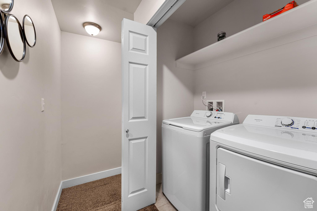 Washroom with light carpet and washer and clothes dryer