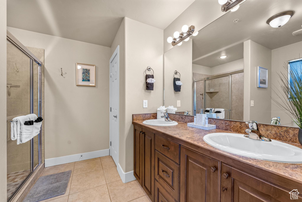 Bathroom with an enclosed shower, large vanity, dual sinks, and tile flooring