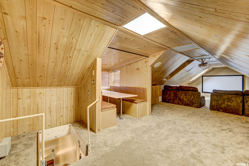 Bonus room with light carpet, vaulted ceiling with skylight, wood ceiling, and wooden walls