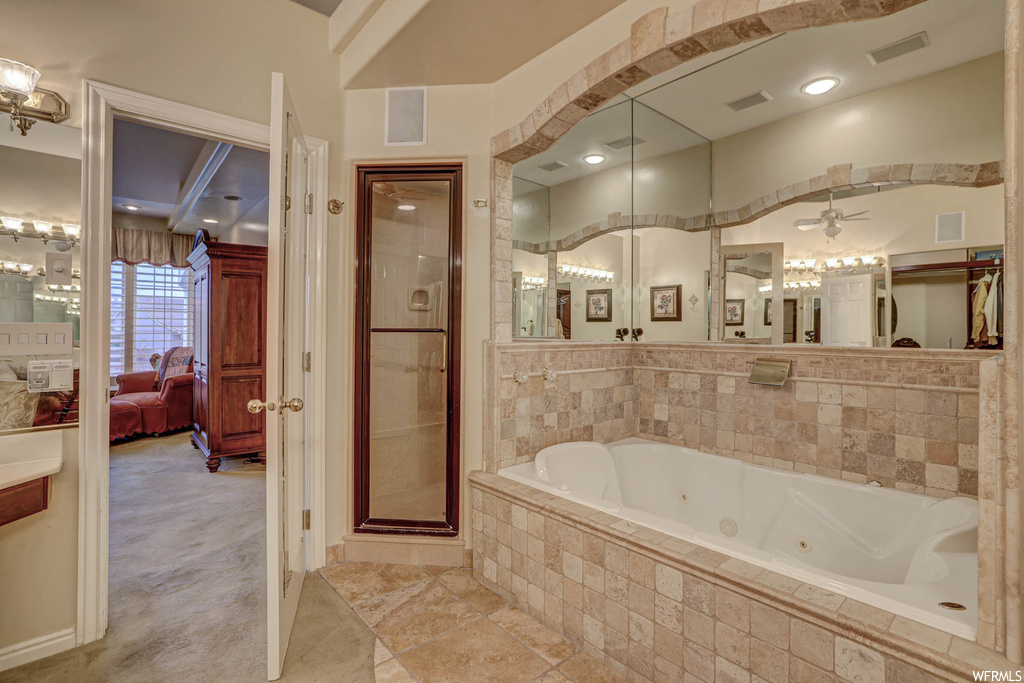 Bathroom featuring separate shower and tub enclosures, ceiling fan, light tile flooring, and mirror