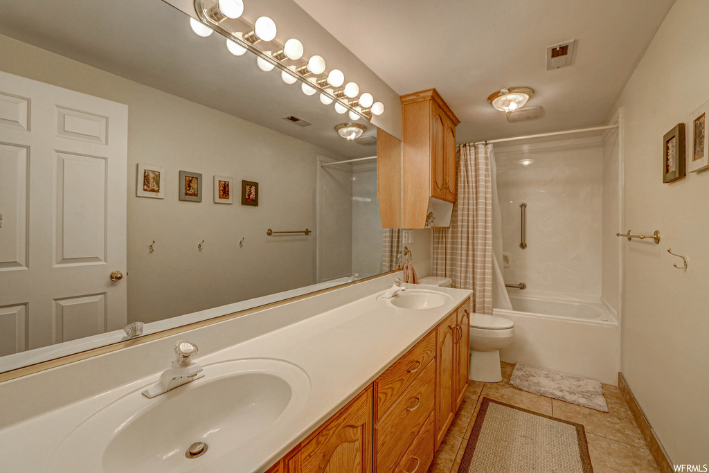 Full bathroom featuring shower / tub combo, light tile floors, double vanity, and mirror