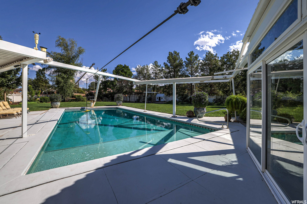 View of swimming pool featuring a patio and a lawn
