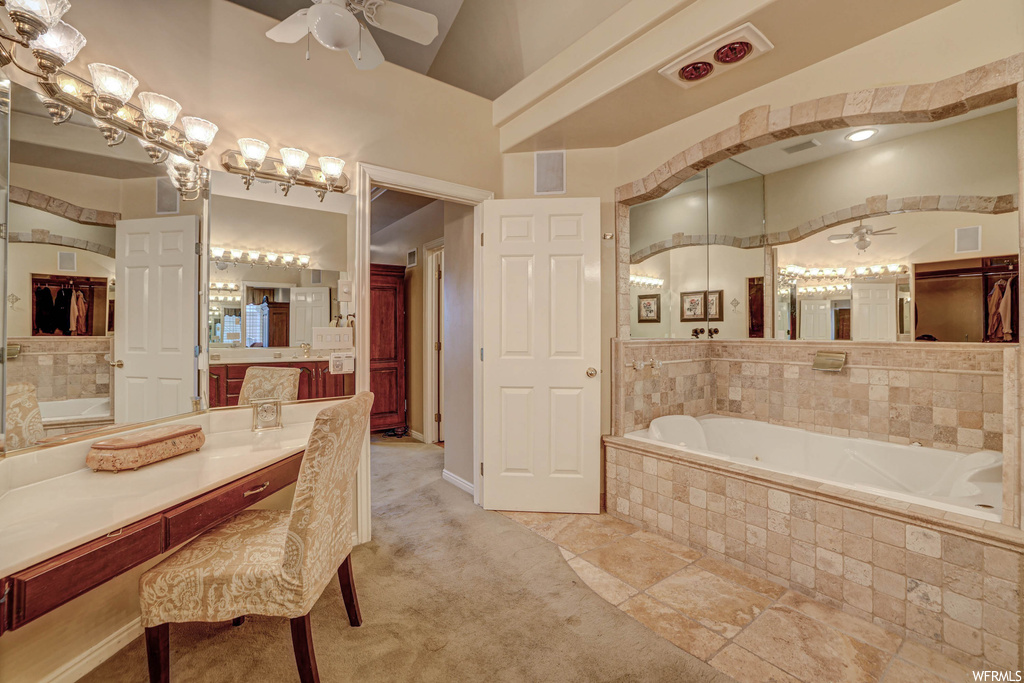 Bathroom featuring vaulted ceiling, vanity, a high ceiling, ceiling fan, a relaxing tiled bath, light tile flooring, and mirror