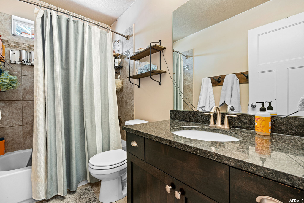 Full bathroom featuring shower / tub combo, a textured ceiling, tile floors, vanity, and mirror