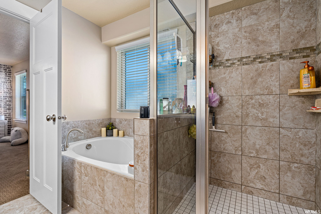 Bathroom featuring a textured ceiling, light tile floors, and independent shower and bath