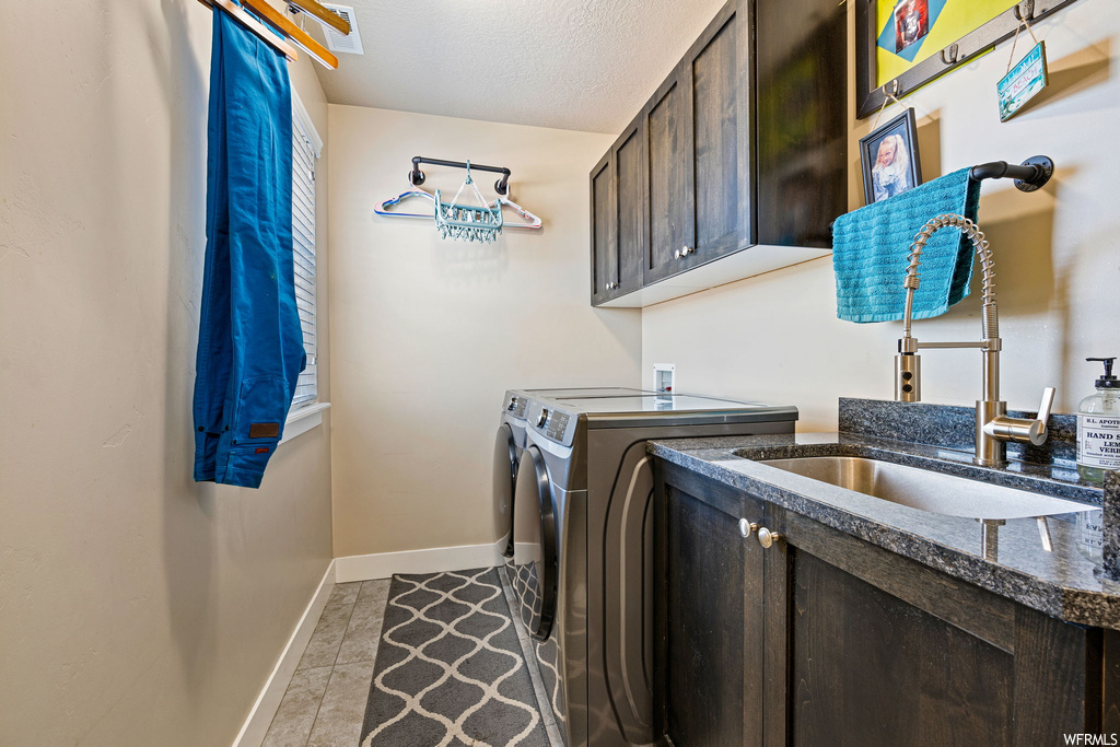 Clothes washing area with washer / dryer, light tile flooring, and a textured ceiling