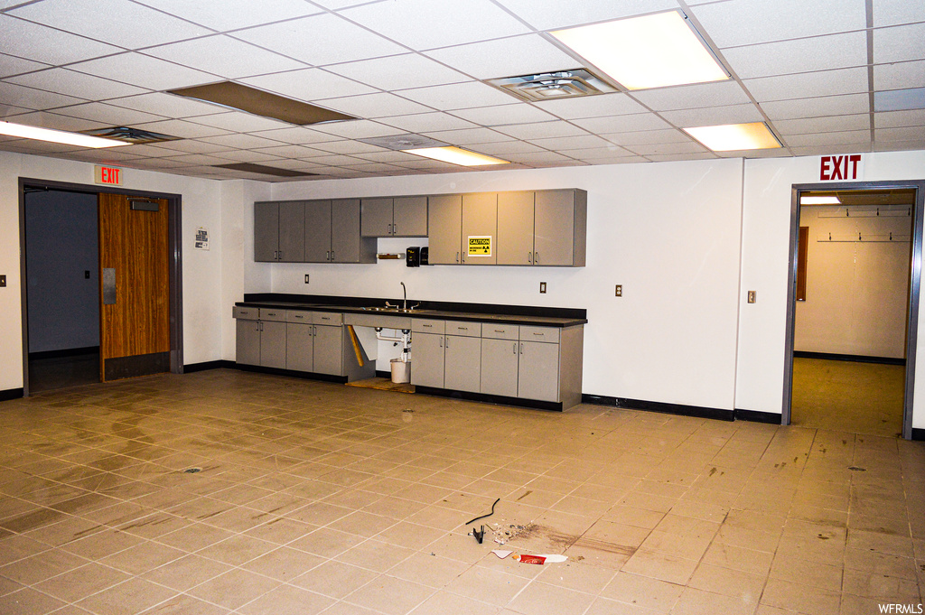Kitchen with light tile floors, a drop ceiling, and dark countertops