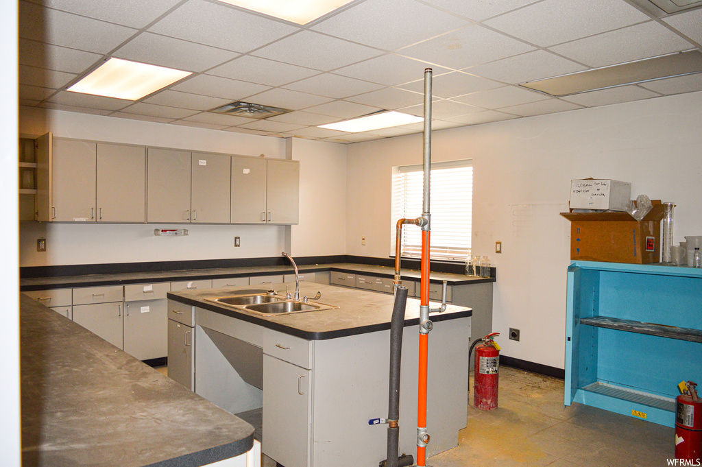 Kitchen featuring white cabinets, a drop ceiling, and light tile flooring