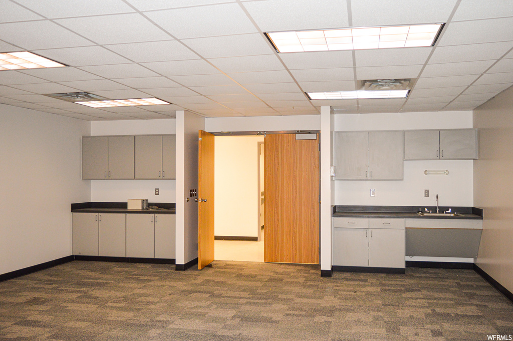 Kitchen featuring carpet flooring, dark countertops, a drop ceiling, and white cabinetry