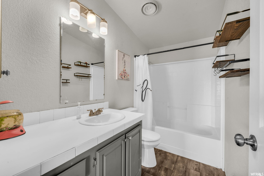 Full bathroom with oversized vanity, lofted ceiling, shower / tub combo, hardwood flooring, and mirror