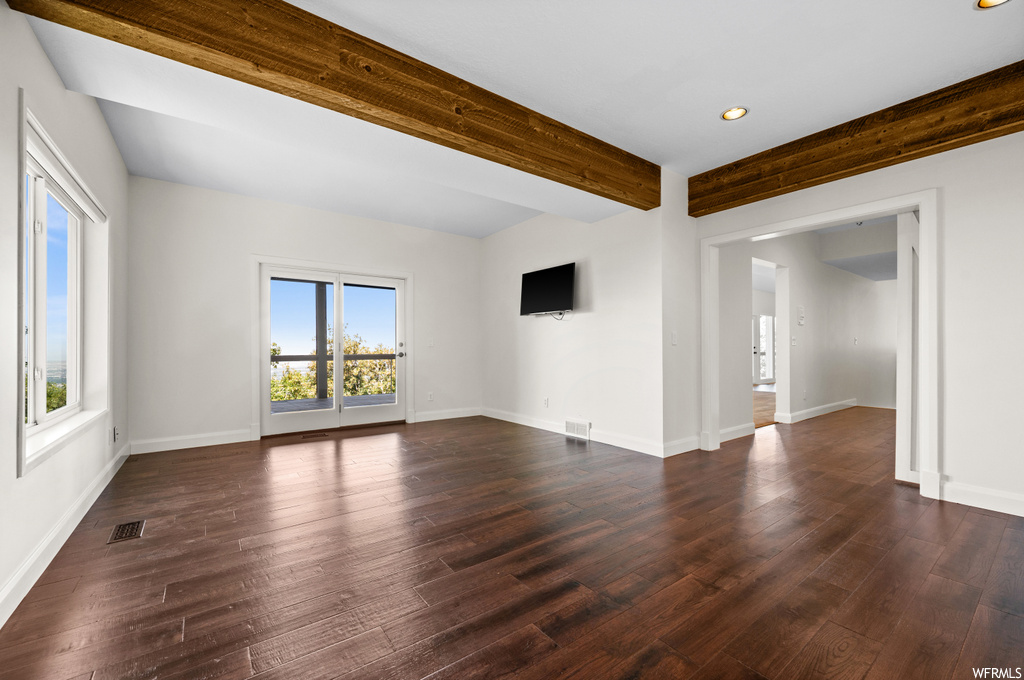 Empty room with beamed ceiling and dark hardwood floors
