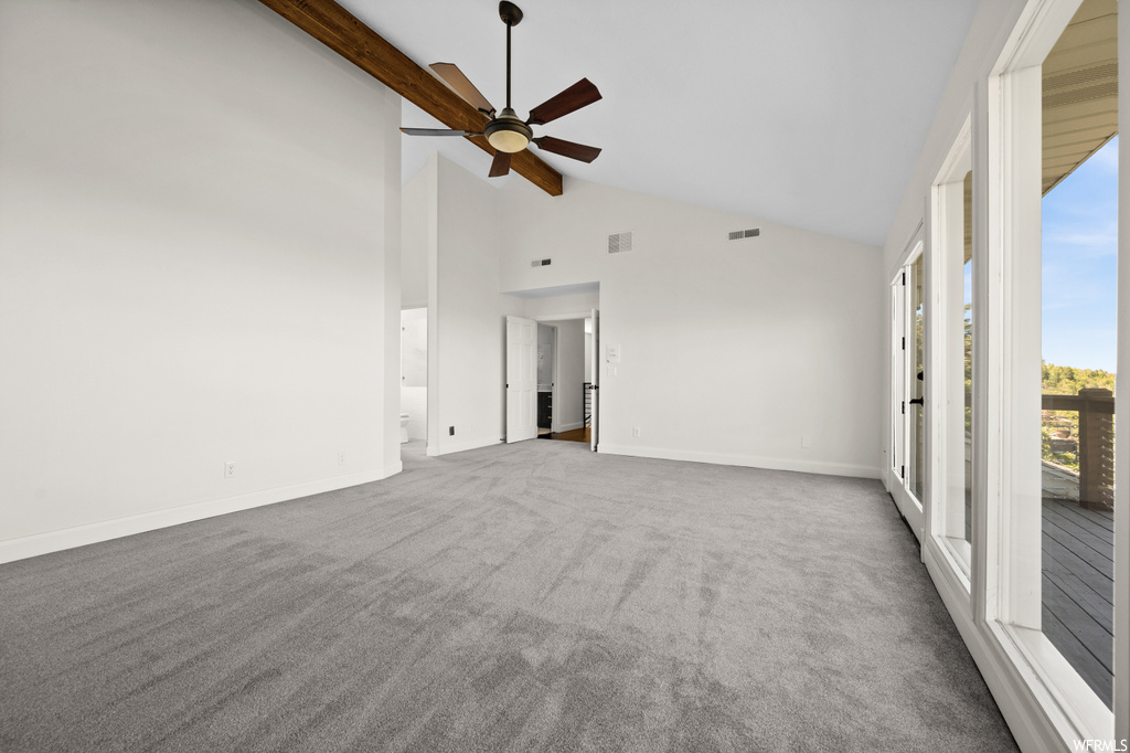 Carpeted spare room with a high ceiling, ceiling fan, and lofted ceiling with beams