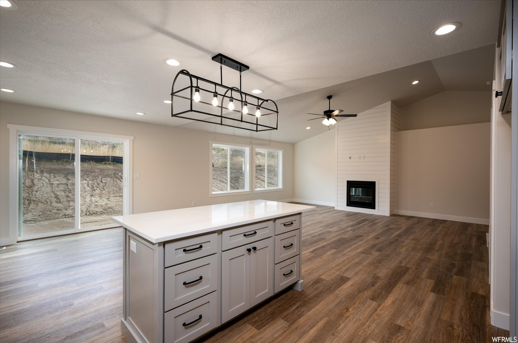 Kitchen featuring pendant lighting, a fireplace, dark hardwood / wood-style flooring, and vaulted ceiling