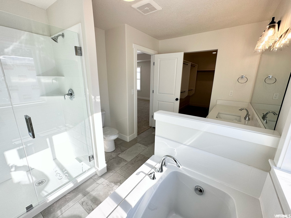 Full bathroom featuring a textured ceiling, light tile floors, separate shower and tub enclosures, dual vanity, and mirror