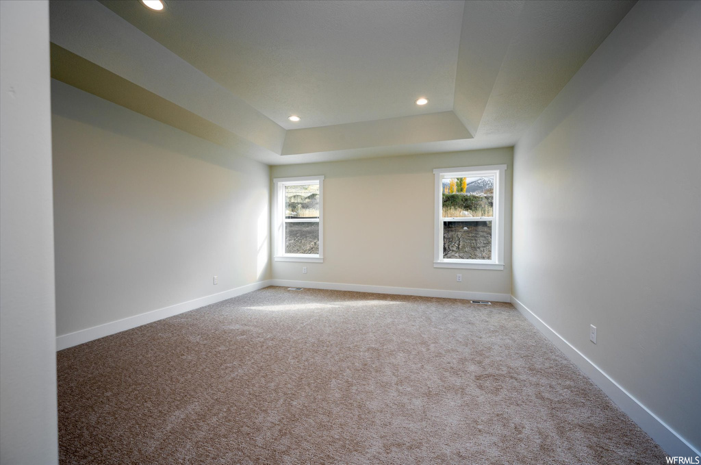 Spare room featuring a tray ceiling and light colored carpet