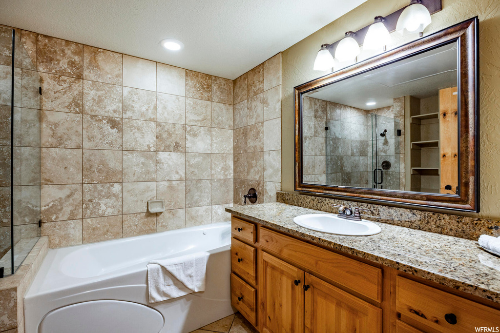 Bathroom featuring tile walls, a textured ceiling, large vanity, mirror, a shower with shower door, and tile floors