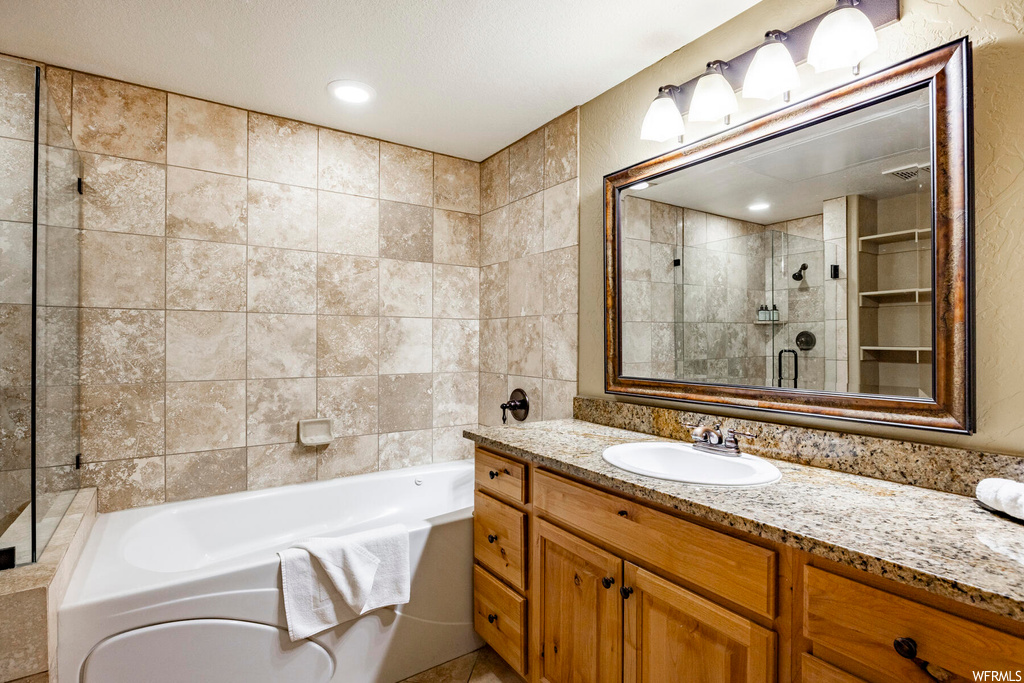 Bathroom with tile walls, a textured ceiling, an enclosed shower, mirror, and vanity