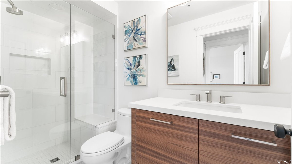 Bathroom featuring vanity, a shower with shower door, and mirror