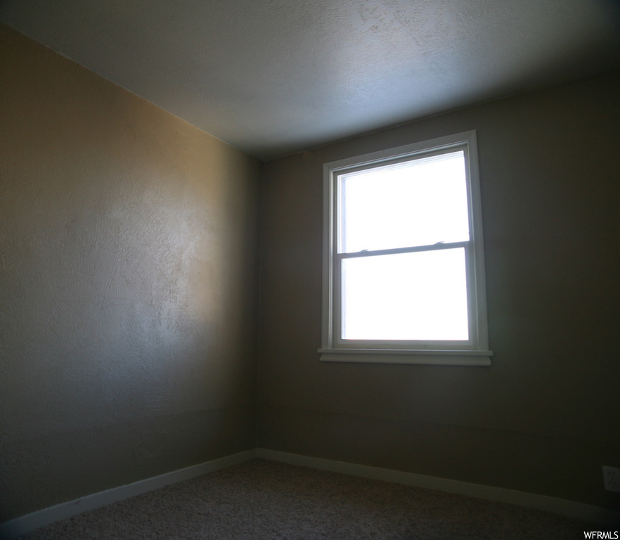 Empty room with a healthy amount of sunlight and dark carpet