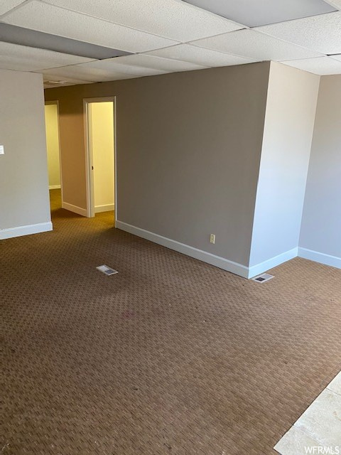 Empty room with a drop ceiling and light carpet