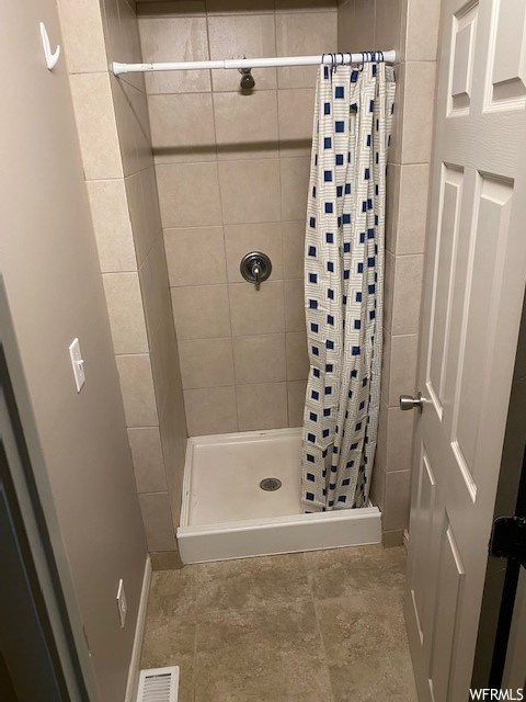 Bathroom featuring a shower with shower curtain and tile floors