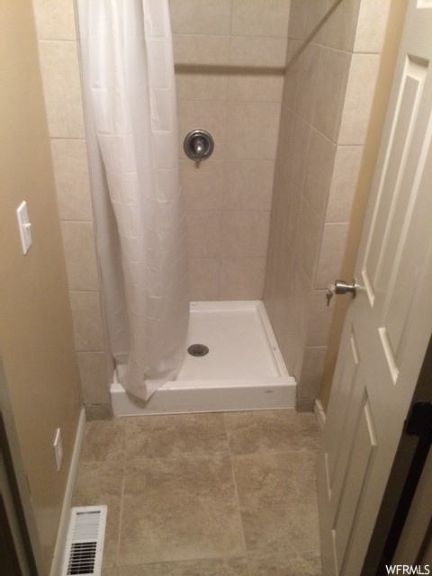 Bathroom with light tile flooring and curtained shower