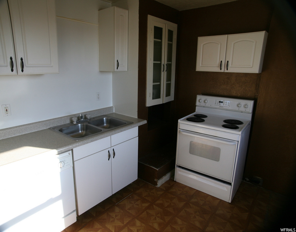 Kitchen with dark parquet flooring, white appliances, and white cabinetry