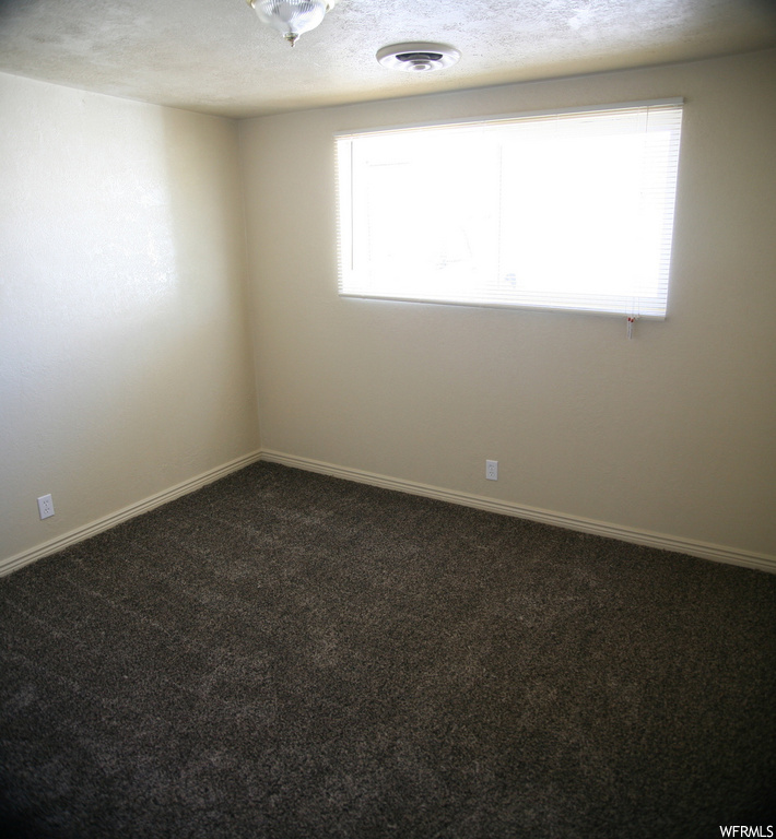 Empty room with a textured ceiling and carpet floors