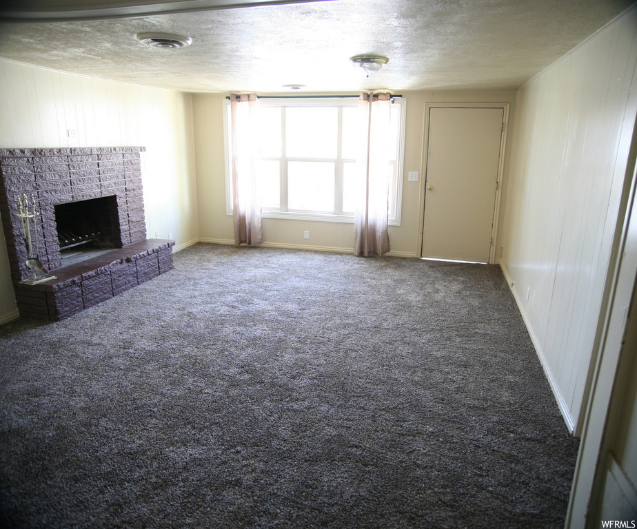 Living room featuring a textured ceiling, a fireplace, and light carpet