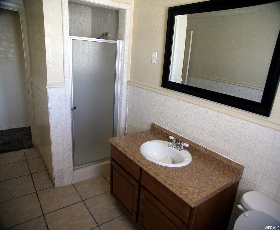 Bathroom featuring mirror, backsplash, oversized vanity, an enclosed shower, tile floors, and tile walls
