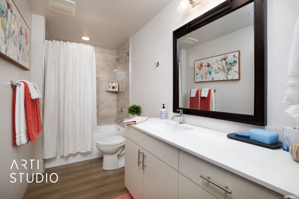 Full bathroom featuring hardwood flooring, shower / bath combo, vanity, and mirror