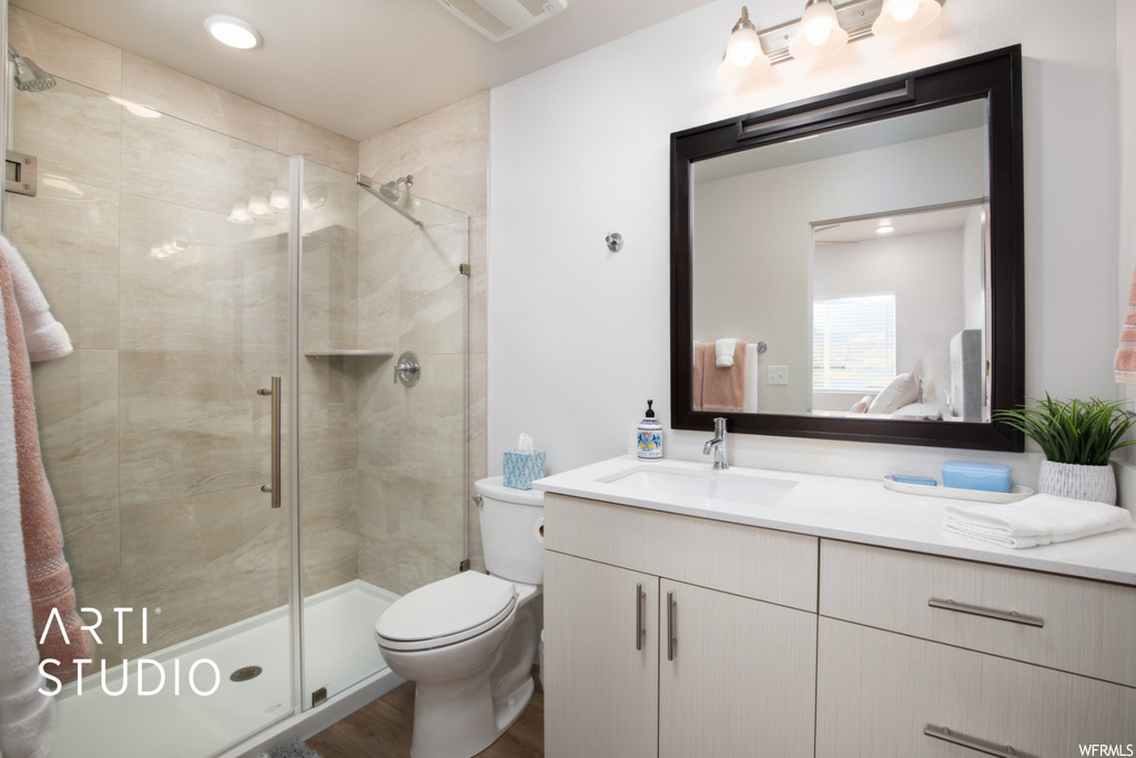 Bathroom with hardwood floors, vanity with extensive cabinet space, mirror, and an enclosed shower