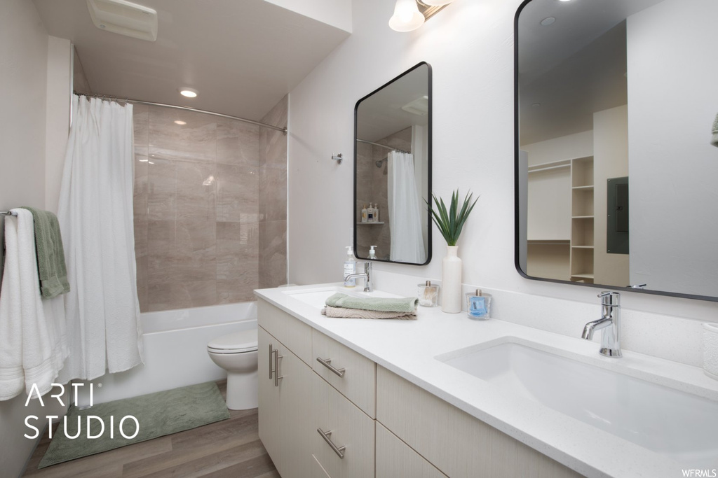 Full bathroom with dual bowl vanity, shower / bathtub combination with curtain, light parquet floors, and mirror