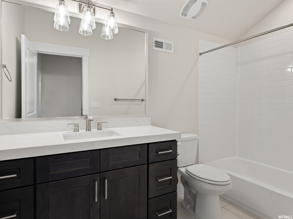 Full bathroom featuring vaulted ceiling, tiled shower / bath, tile flooring, vanity, and mirror