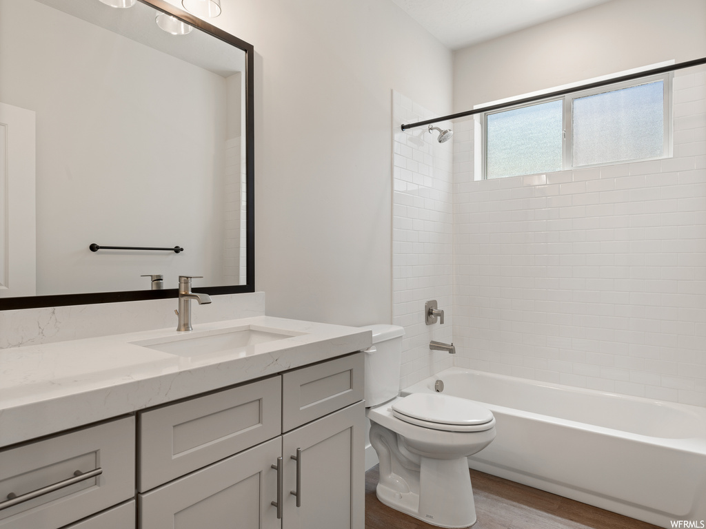 Full bathroom featuring vanity, hardwood floors, tiled shower / bath, and mirror