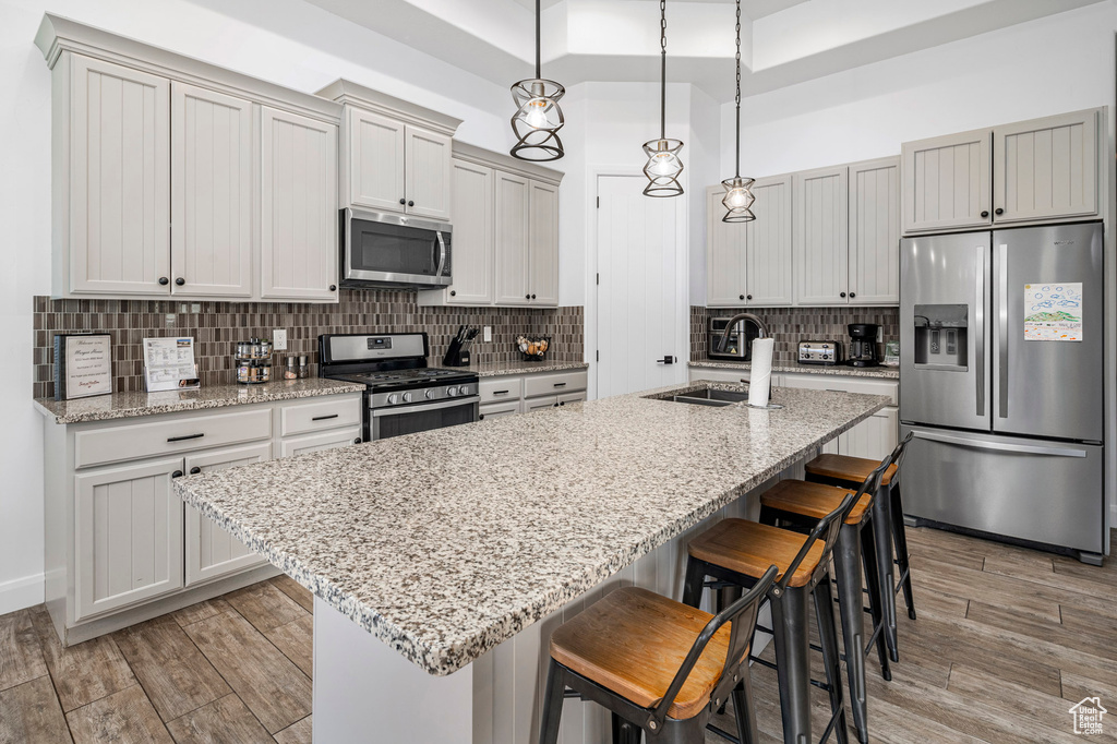 Kitchen with decorative light fixtures, a breakfast bar, appliances with stainless steel finishes, and backsplash