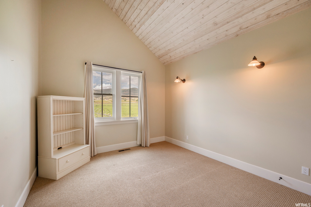 Carpeted spare room with vaulted ceiling and wooden ceiling