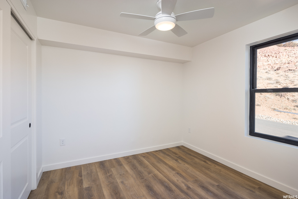 Empty room with ceiling fan and dark wood-type flooring