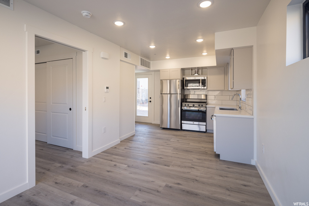 Kitchen featuring light hardwood / wood-style flooring, sink, stainless steel appliances, and backsplash