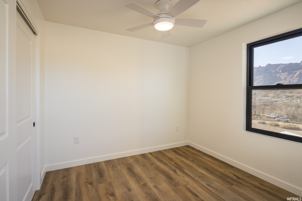 Unfurnished room featuring ceiling fan and dark hardwood / wood-style flooring