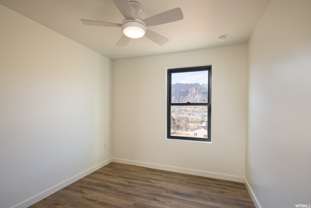 Spare room featuring dark wood-type flooring and ceiling fan