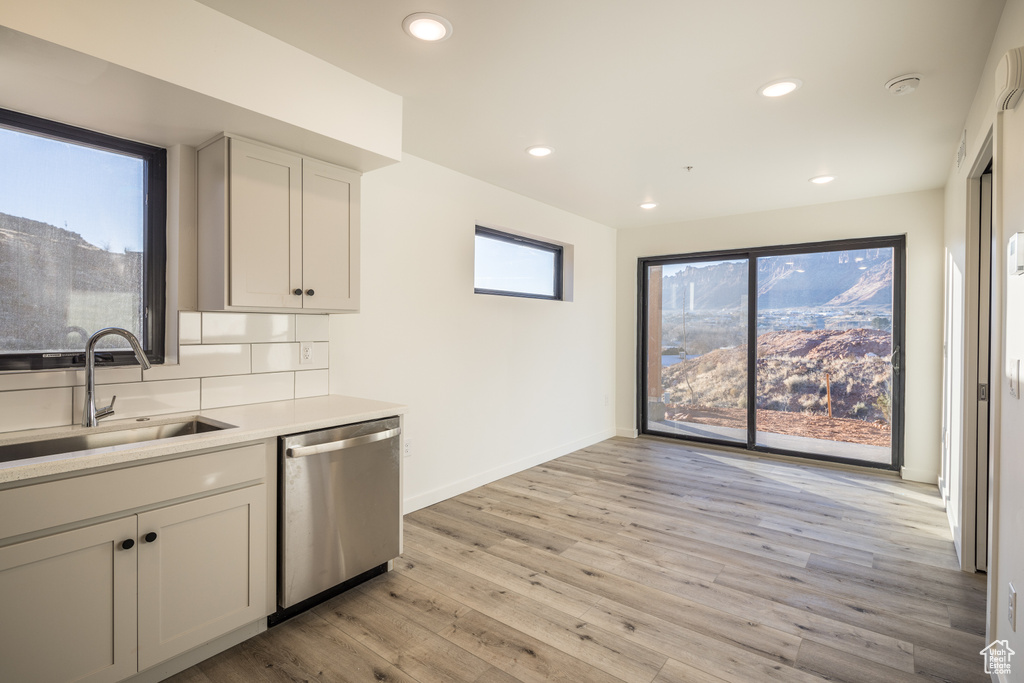 Kitchen featuring stainless steel dishwasher, a sink, light wood finished floors, light countertops, and recessed lighting
