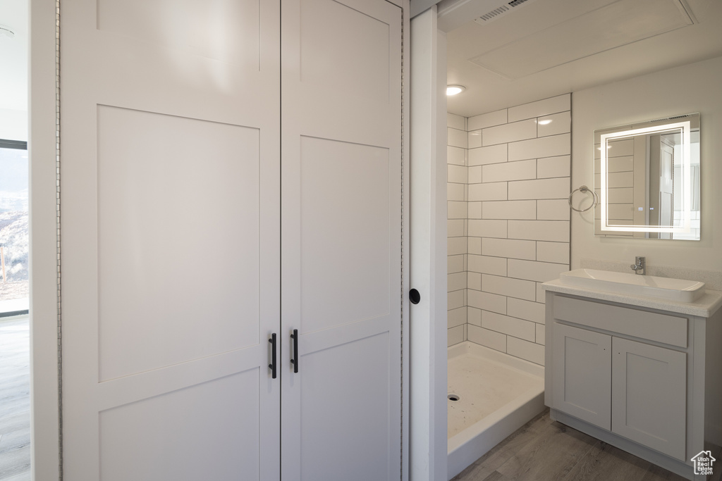 Full bathroom with vanity, a shower stall, and wood finished floors