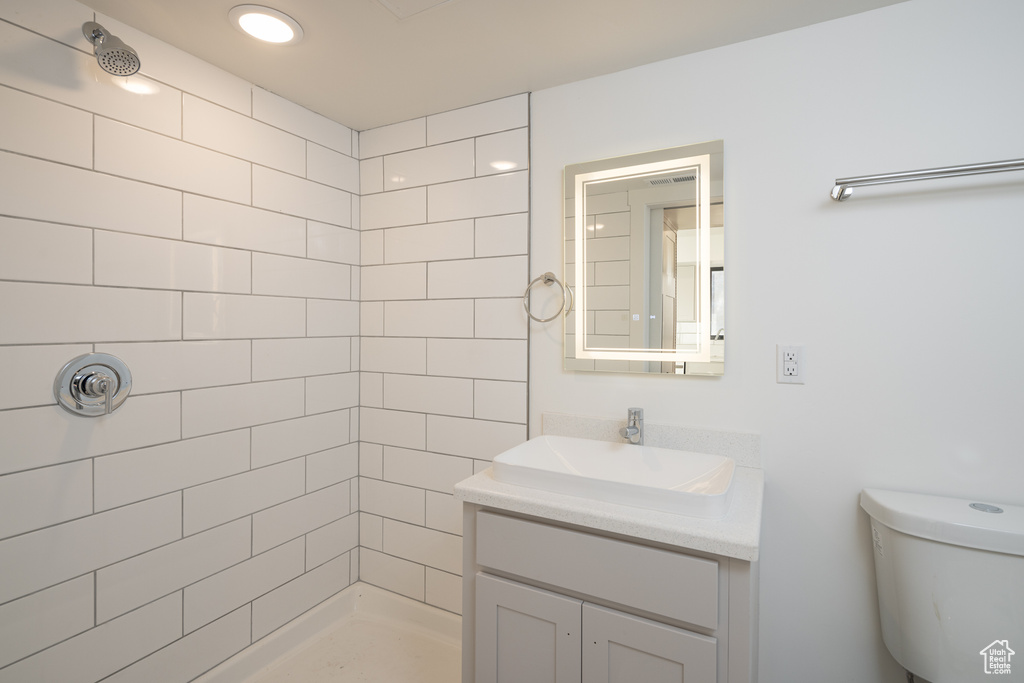 Full bathroom featuring toilet, a tile shower, and vanity