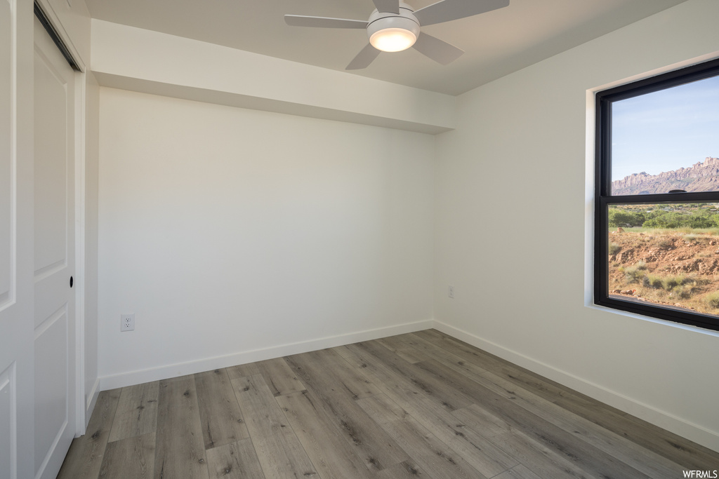 Hardwood floored empty room featuring ceiling fan