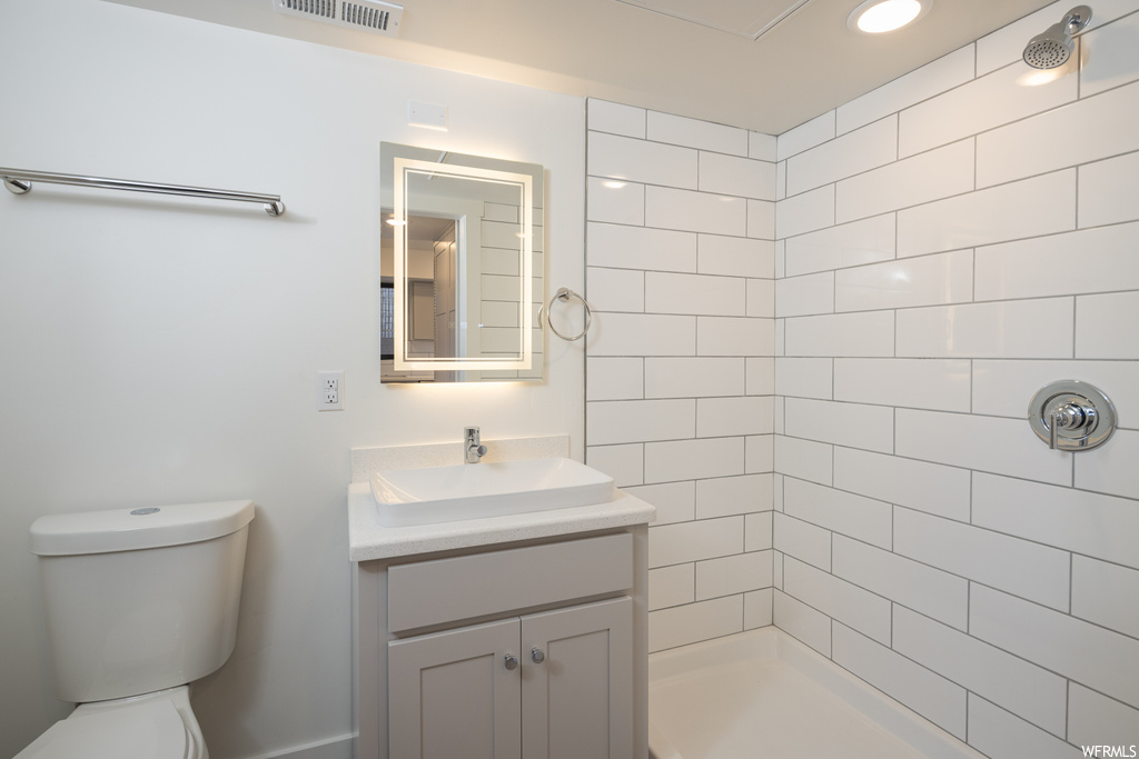 Bathroom with a tile shower, vanity with extensive cabinet space, and mirror